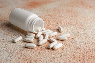 White medical bottle and pills on color textured surface, space for text