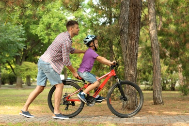 Photo of Dad teaching son to ride bicycle in park