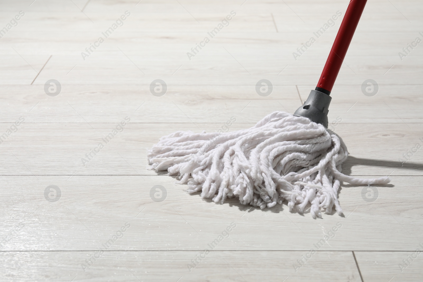 Photo of Cleaning white parquet floor with mop, closeup. Space for text