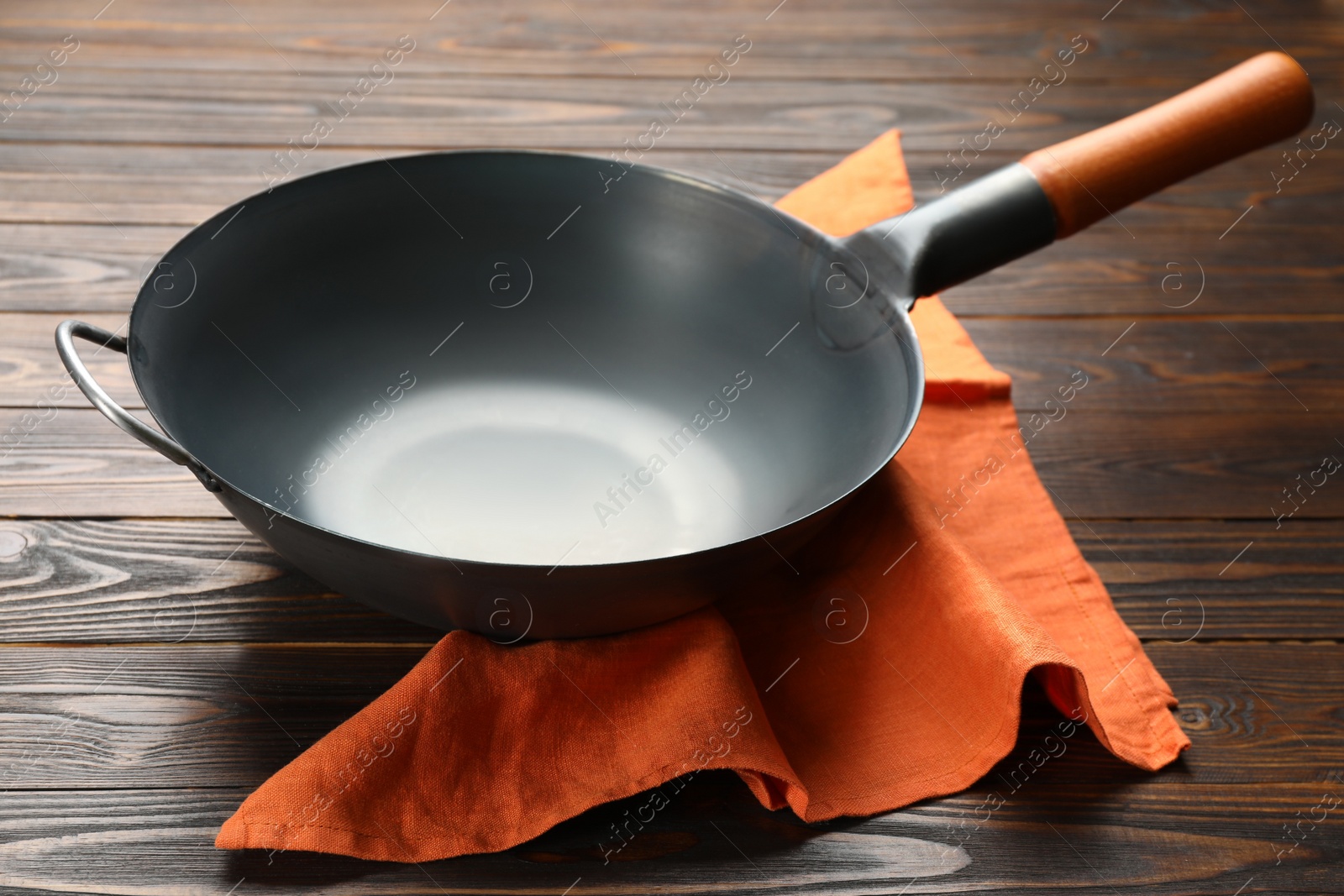 Photo of Empty iron wok with napkin on wooden table