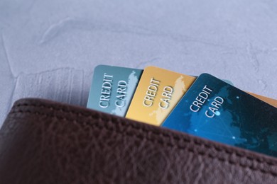 Photo of Credit cards in leather wallet on grey textured table, closeup