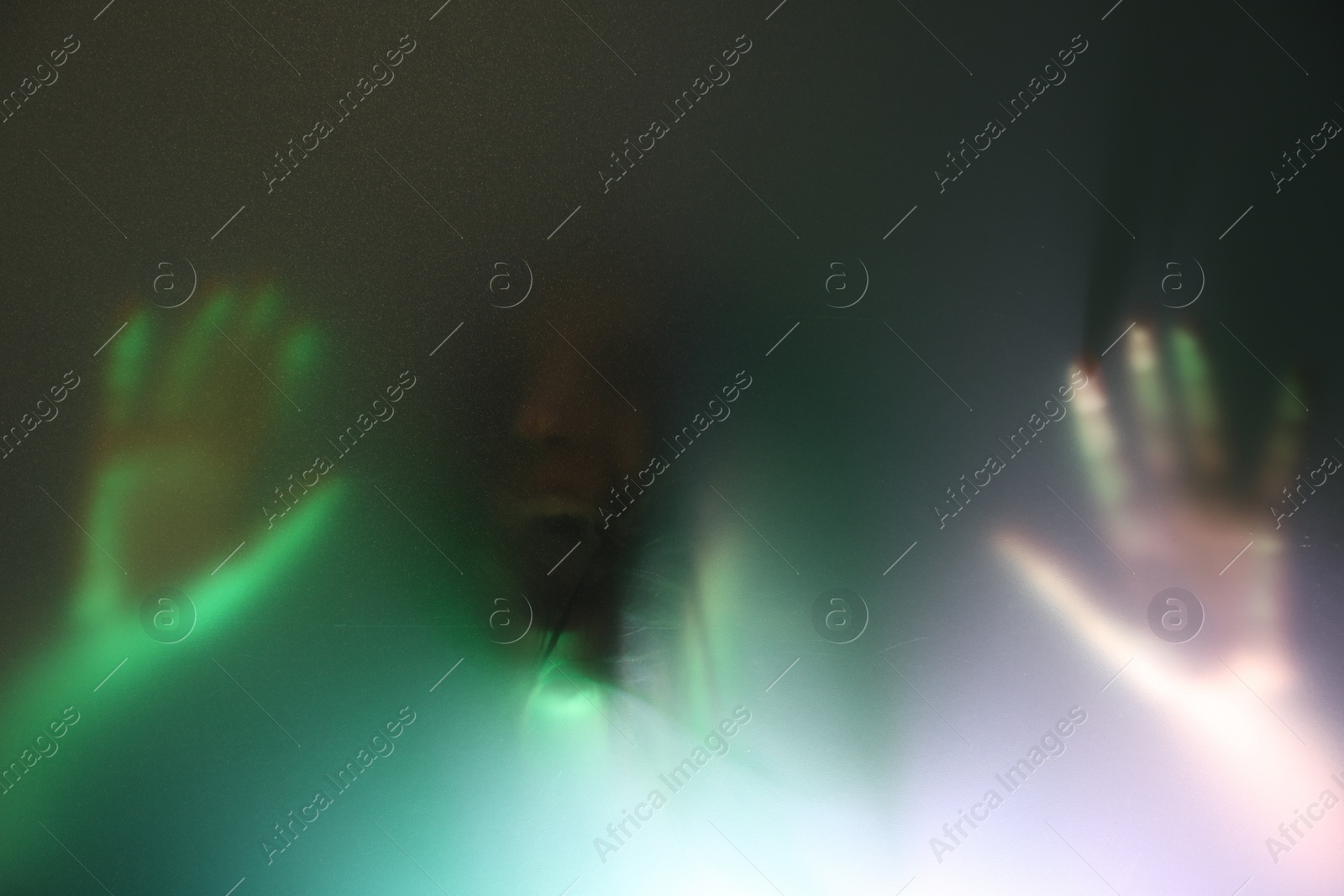 Photo of Silhouette of creepy ghost behind glass against color background