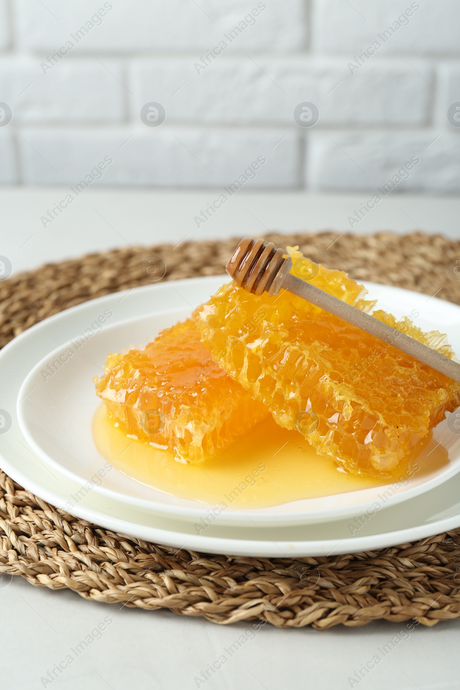 Photo of Natural honeycombs with tasty honey and dipper on white table