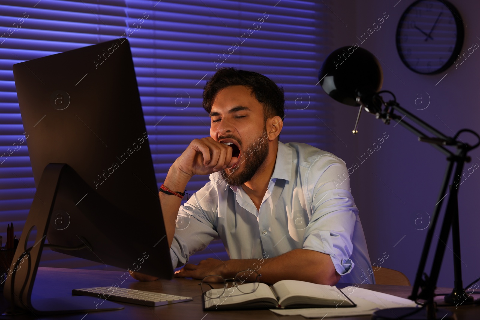 Photo of Tired young man working late in office