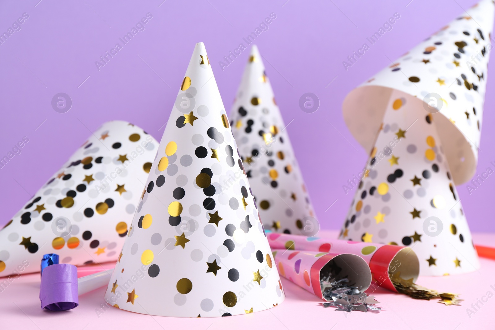 Photo of Party hats, confetti and blowers on color background