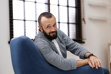 Portrait of handsome mature man sitting in armchair at home