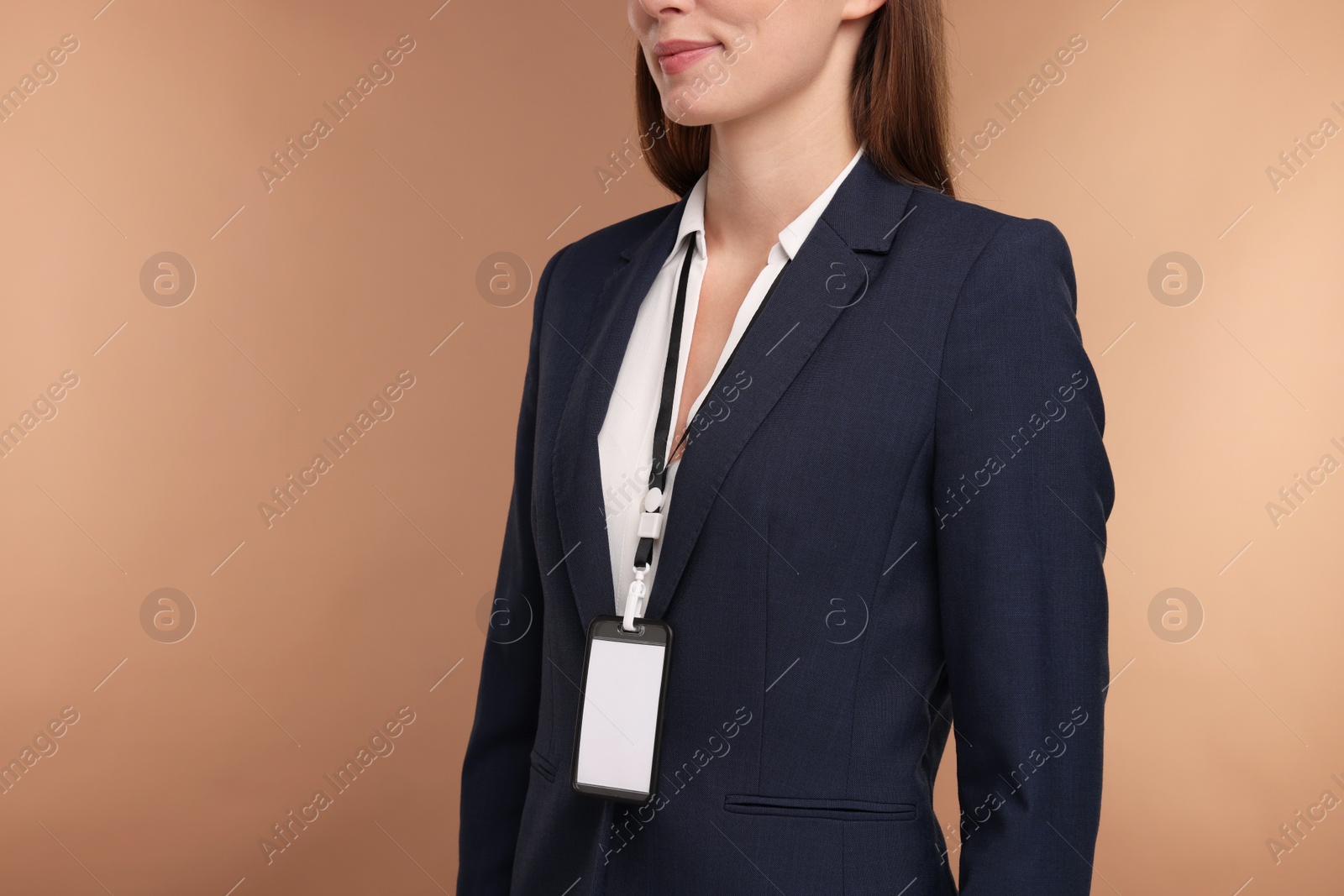 Photo of Woman with blank badge on light brown background, closeup. Space for text