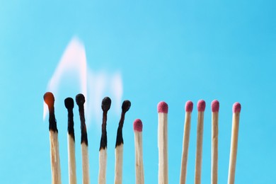 Photo of Burning and whole matches on light blue background. Space for text