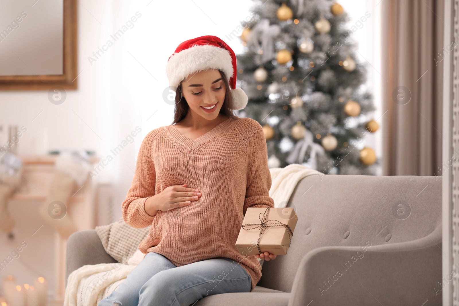 Photo of Happy pregnant woman with Christmas gift box at home. Expecting baby