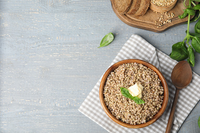 Photo of Tasty buckwheat porridge with butter on grey wooden table, flat lay. Space for text