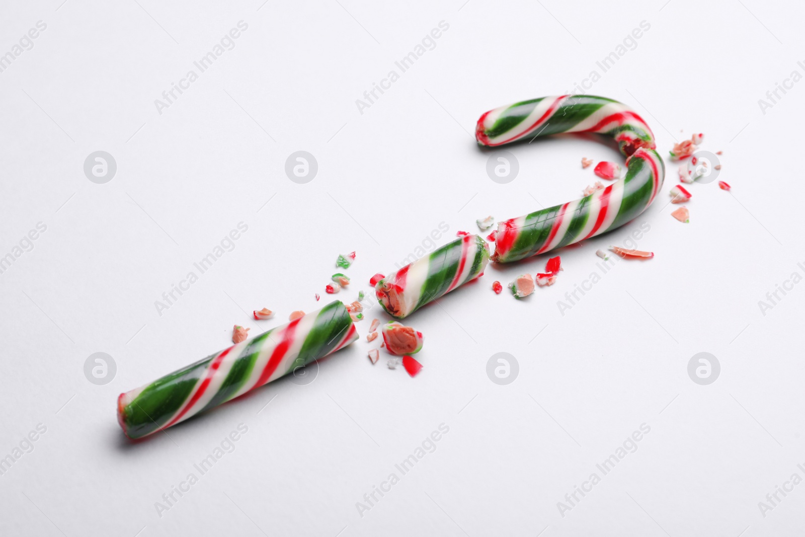 Photo of Broken sweet Christmas candy cane on white background