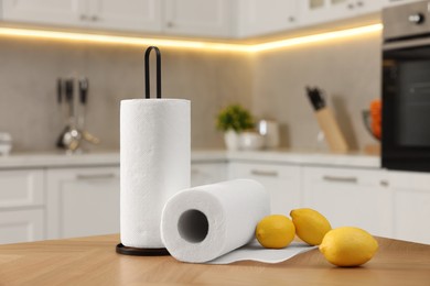 Photo of Rolls of white paper towels and lemons on wooden table in kitchen