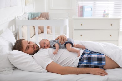 Photo of Tired young father sleeping with his baby in bed at home