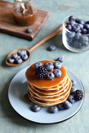 Tasty pancakes with berries and syrup on plate