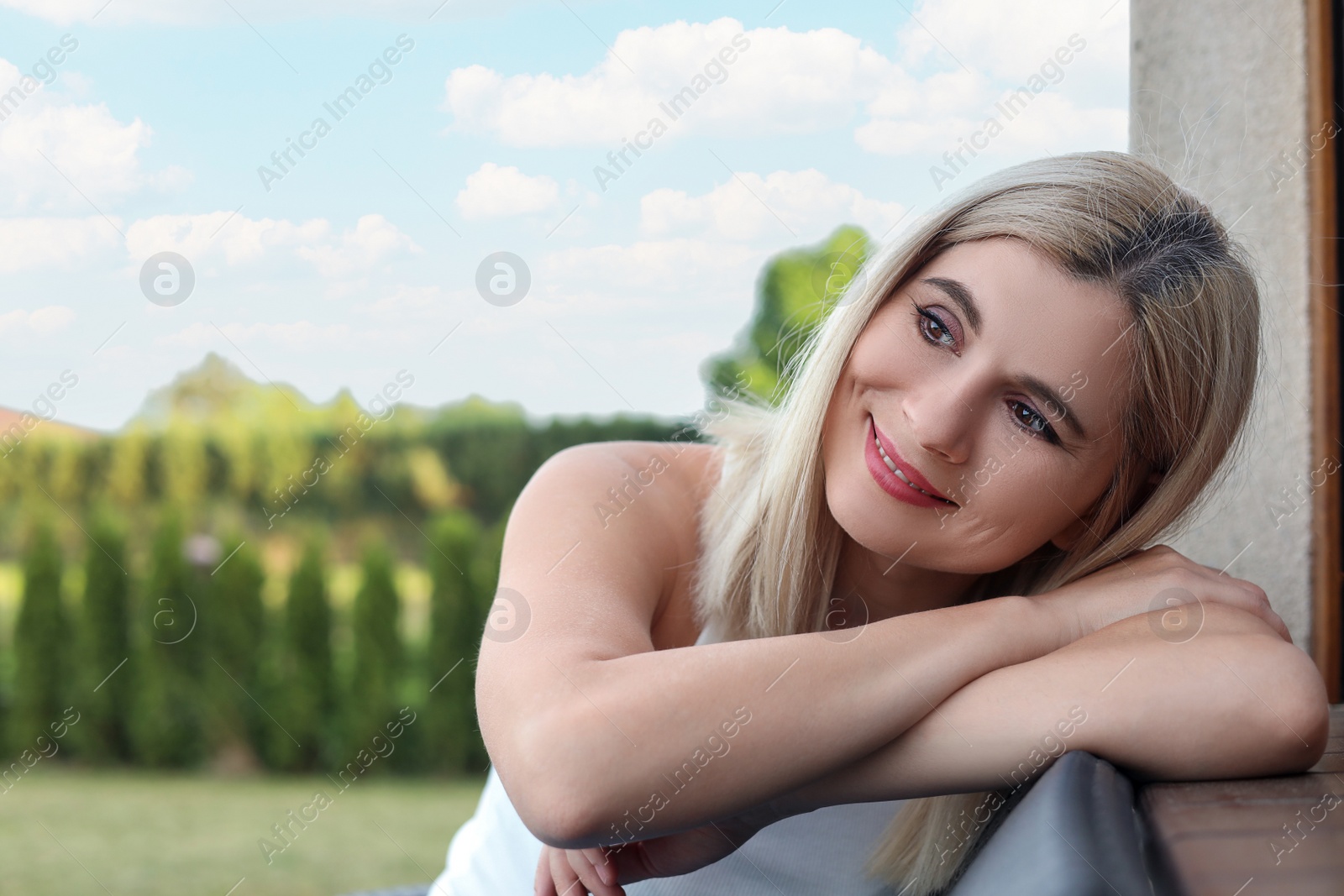 Photo of Portrait of beautiful woman sitting near house in yard, space for text