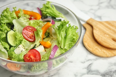 Photo of Tasty fresh Greek salad on white marble table, closeup