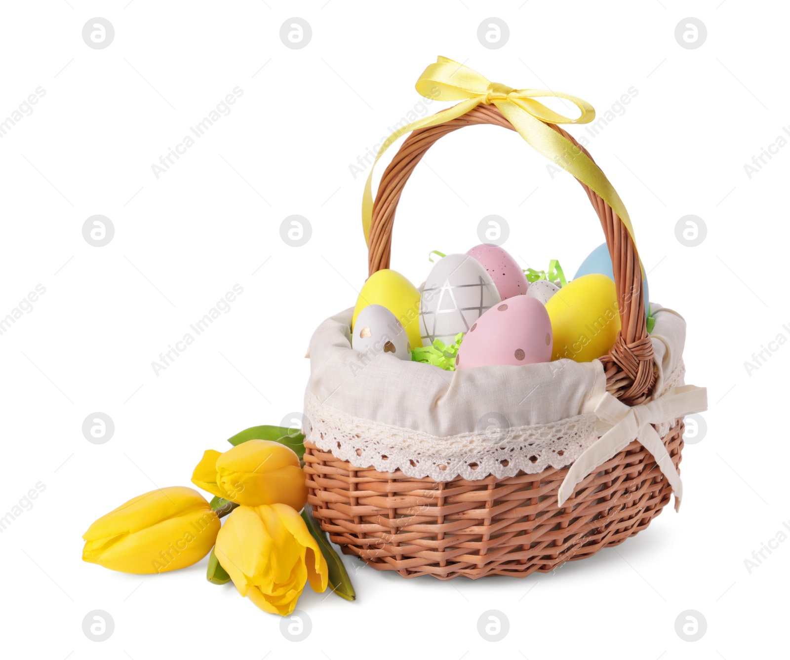 Photo of Wicker basket with beautifully painted Easter eggs and tulips isolated on white