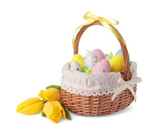 Wicker basket with beautifully painted Easter eggs and tulips isolated on white