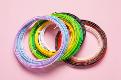 Colorful plastic filaments for 3D pen on pink background, above view
