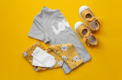 Stylish child clothes and shoes on yellow background, flat lay