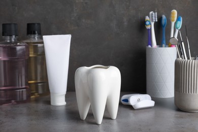 Photo of Tooth model and oral care products on grey table