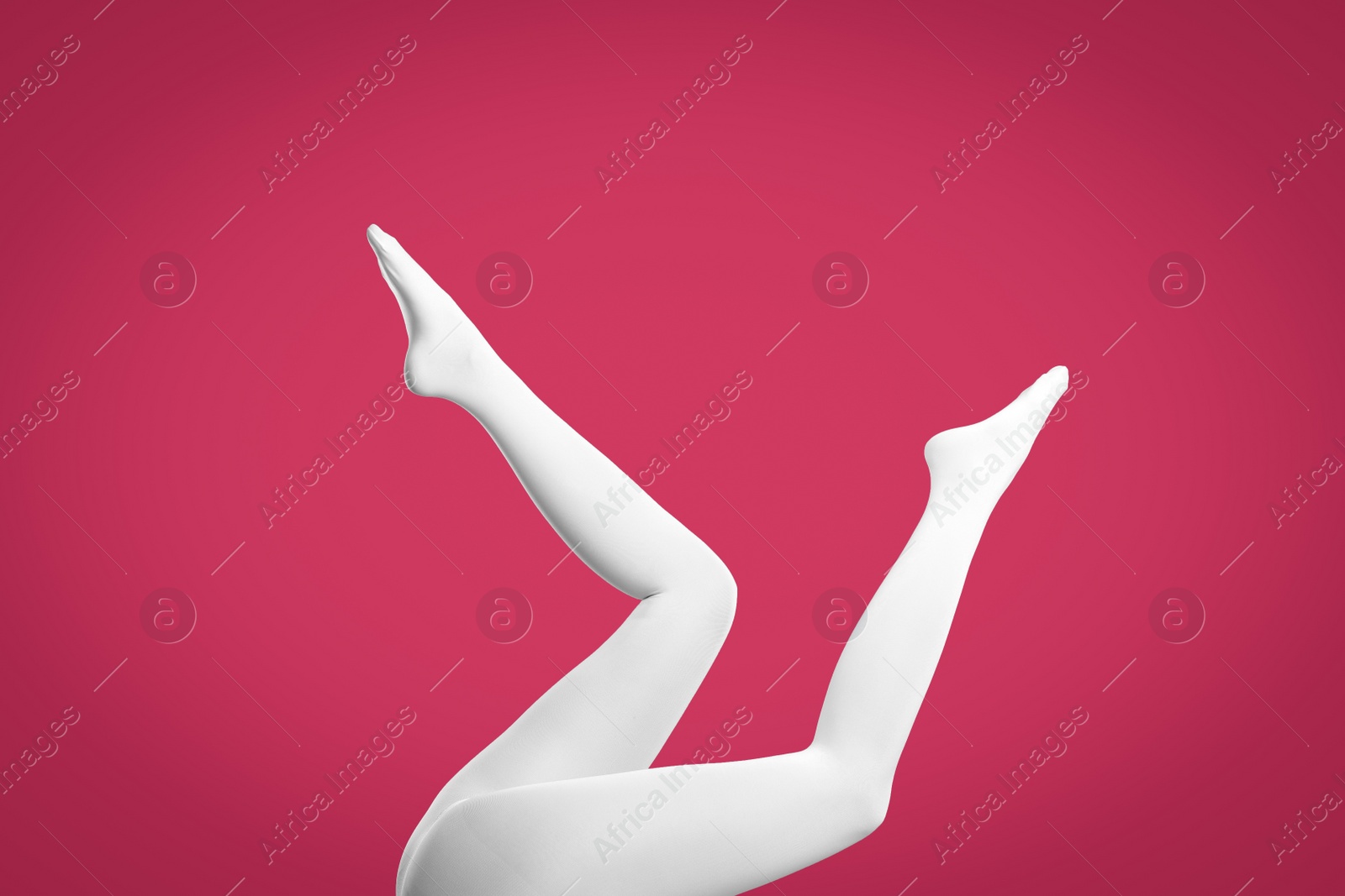 Photo of Woman wearing white tights on crimson background, closeup of legs