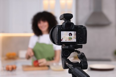 Photo of Food blogger recording video in kitchen, focus on camera