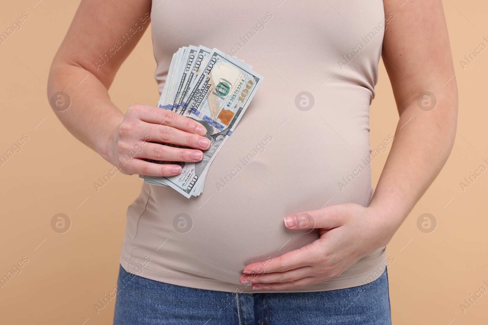 Photo of Surrogate mother. Pregnant woman with dollar banknotes on beige background, closeup