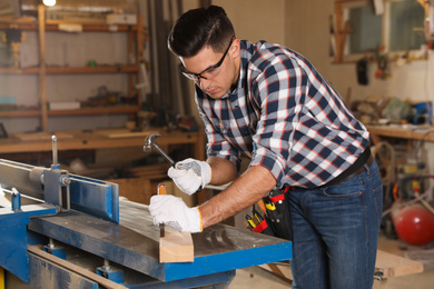 Photo of Professional carpenter working with wooden plank in workshop