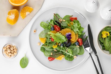 Photo of Delicious salad, ingredients and cutlery on white table, flat lay