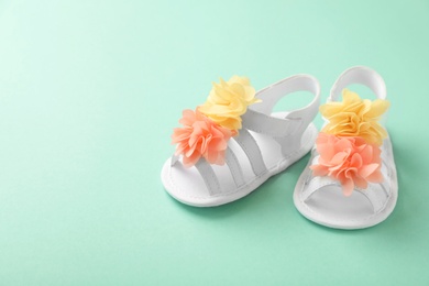 Photo of Pair of baby sandals decorated with flowers on color background