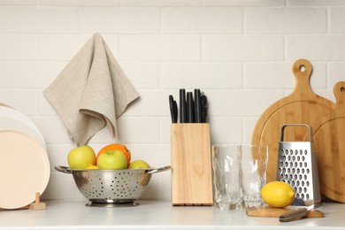 Photo of Different cooking utensils, dishware and fruits on kitchen counter