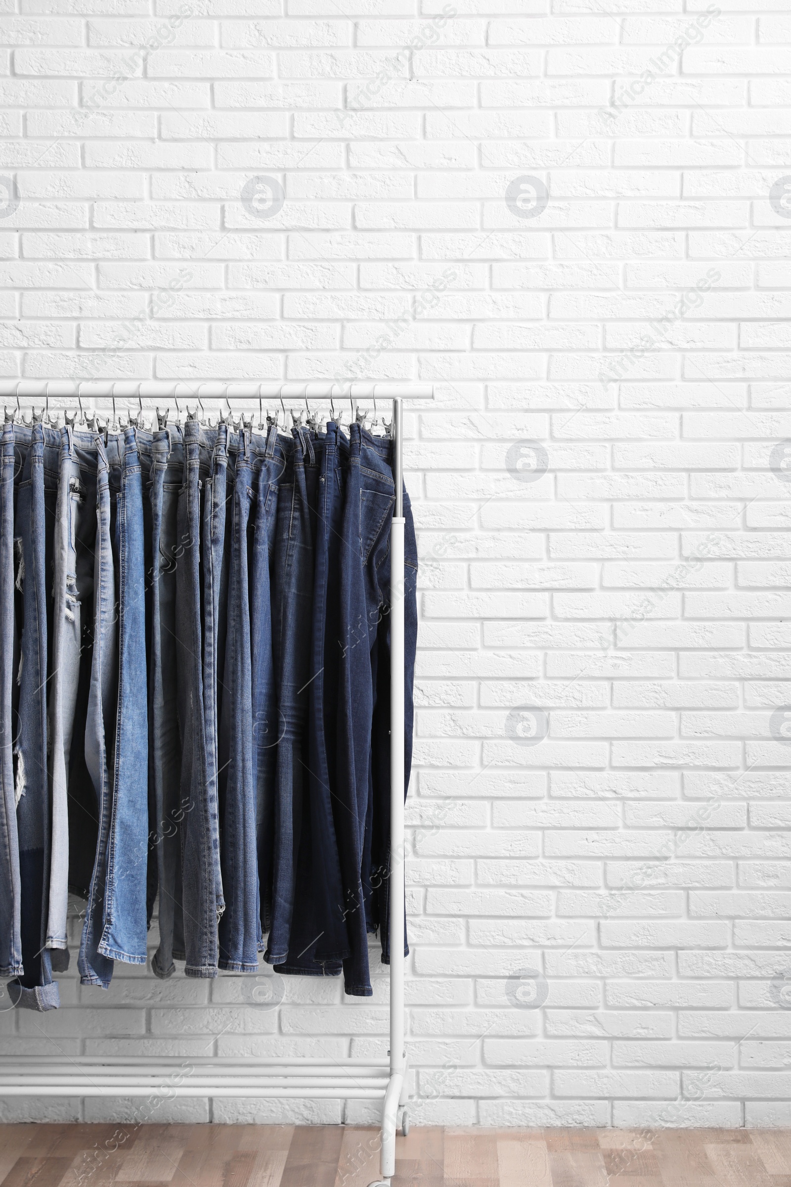 Photo of Rack with stylish jeans near brick wall