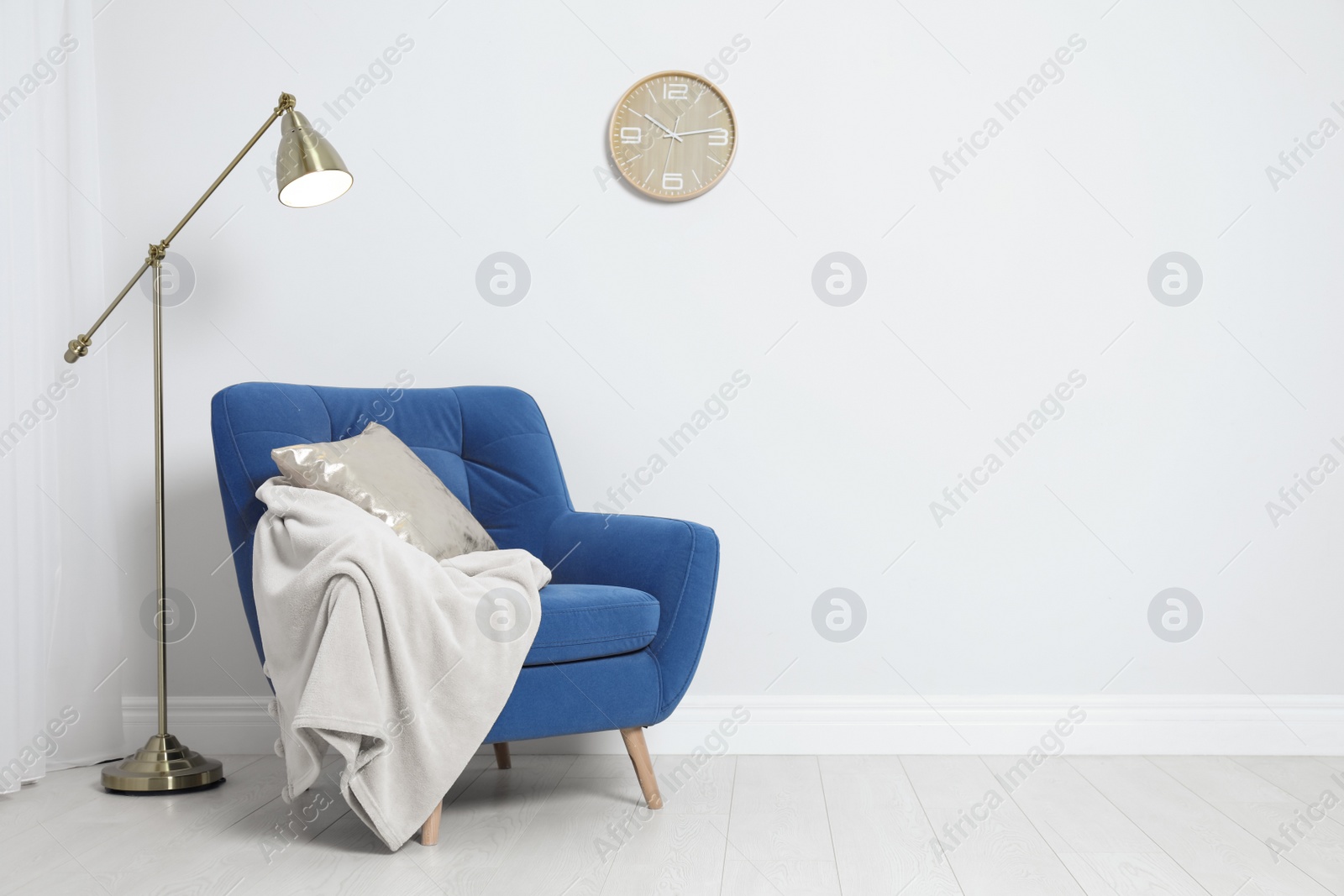 Photo of Stylish armchair with pillow and plaid near white wall, space for text. Interior design