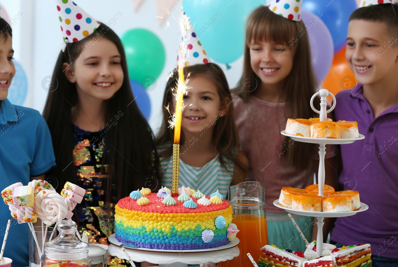 Photo of Happy children near cake with firework candle at birthday party indoors