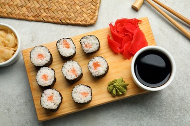 Photo of Tasty sushi rolls served on grey table, flat lay