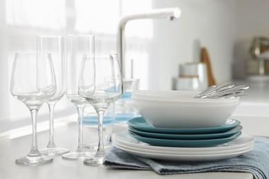 Photo of Different clean dishware, cutlery and glasses on countertop in kitchen
