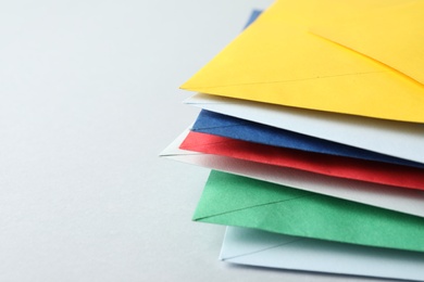 Stack of colorful paper envelopes on light background, closeup. Space for text