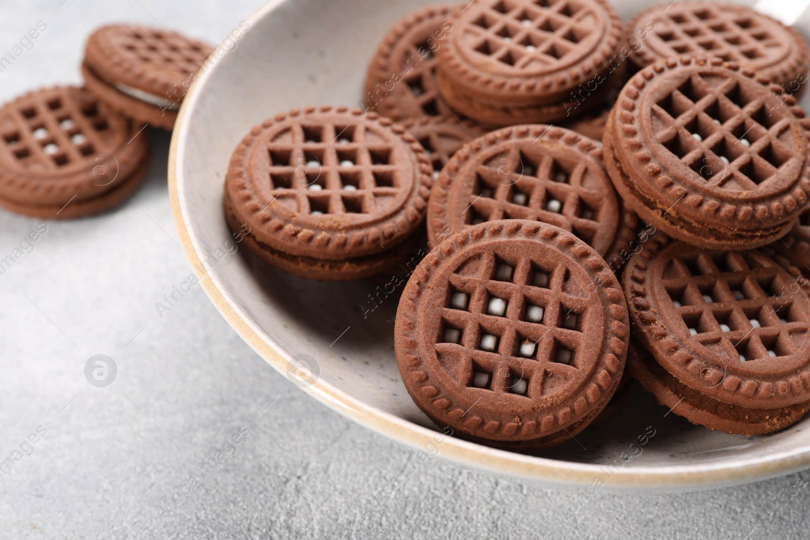 Photo of Tasty chocolate sandwich cookies with cream on light grey table, closeup