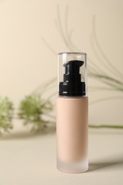 Bottle of skin foundation on beige background. Makeup product