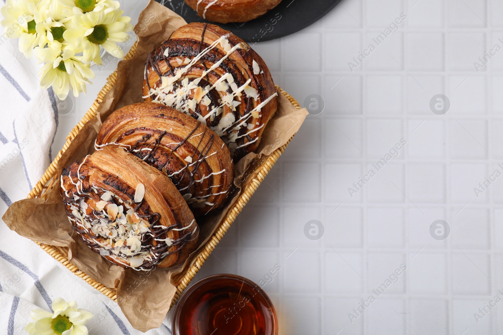 Photo of Sweet buns. Delicious rolls with toppings and almond on white tiled table, flat lay. Space for text