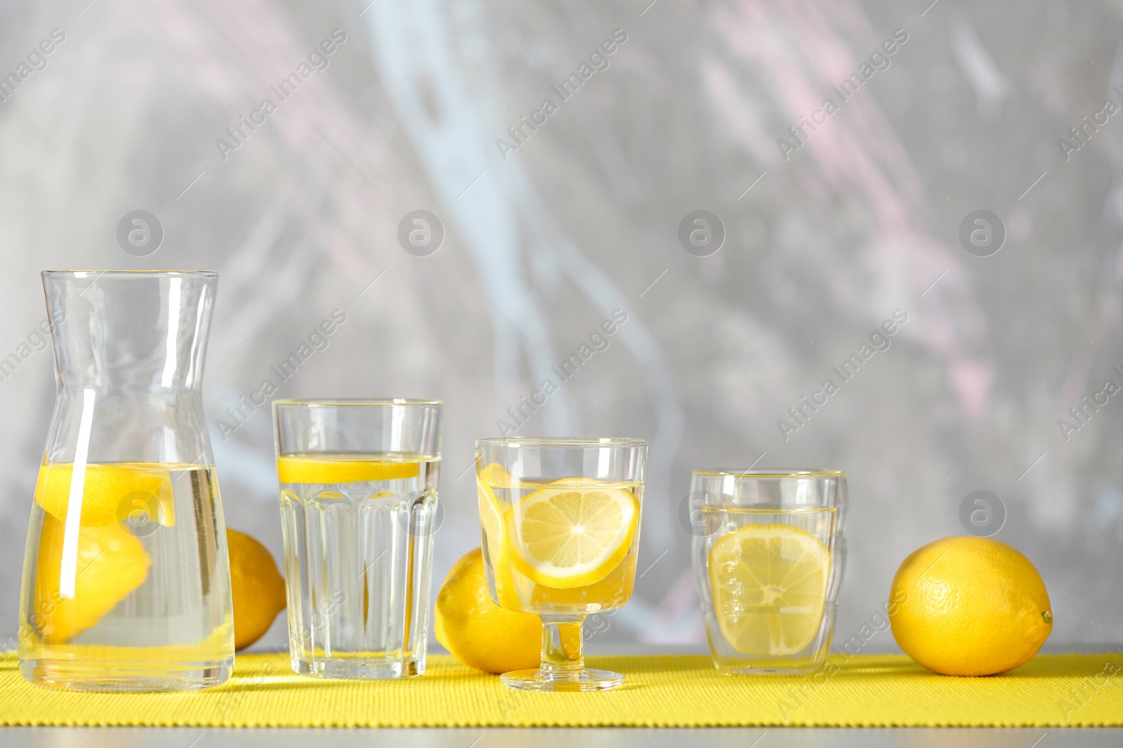 Photo of Glassware with water and slices of lemon on table