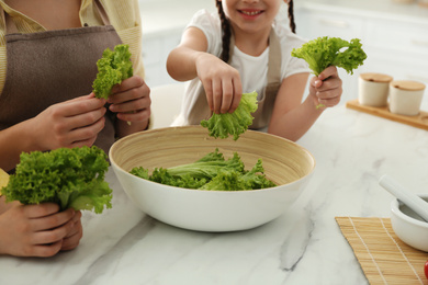 Photo of Family cooking salad together in kitchen, closeup