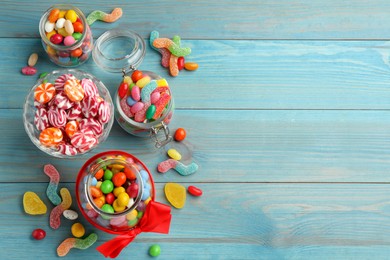 Photo of Jars with different delicious candies on light blue wooden table, flat lay. Space for text