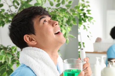 Photo of Man rinsing mouth with mouthwash in bathroom. Teeth care