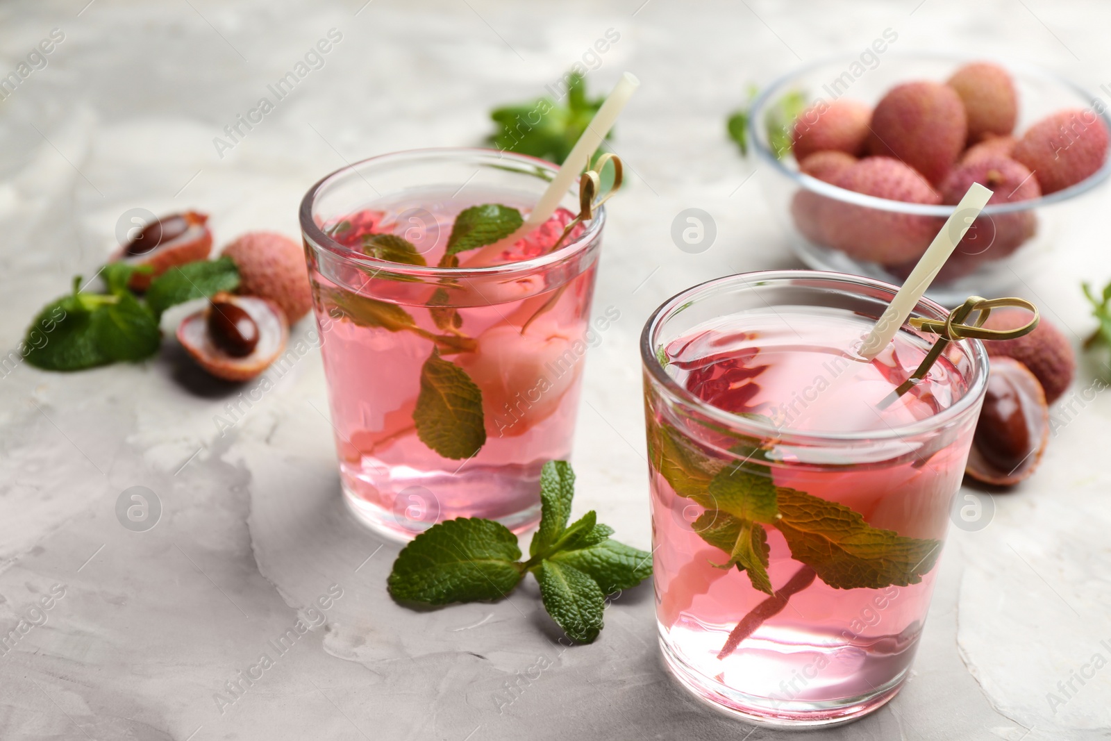 Photo of Lychee cocktail with mint and fresh fruits on grey marble table