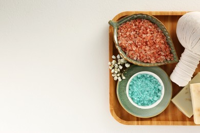 Aromatic sea salt, beautiful flowers and different spa products on white table, top view. Space for text