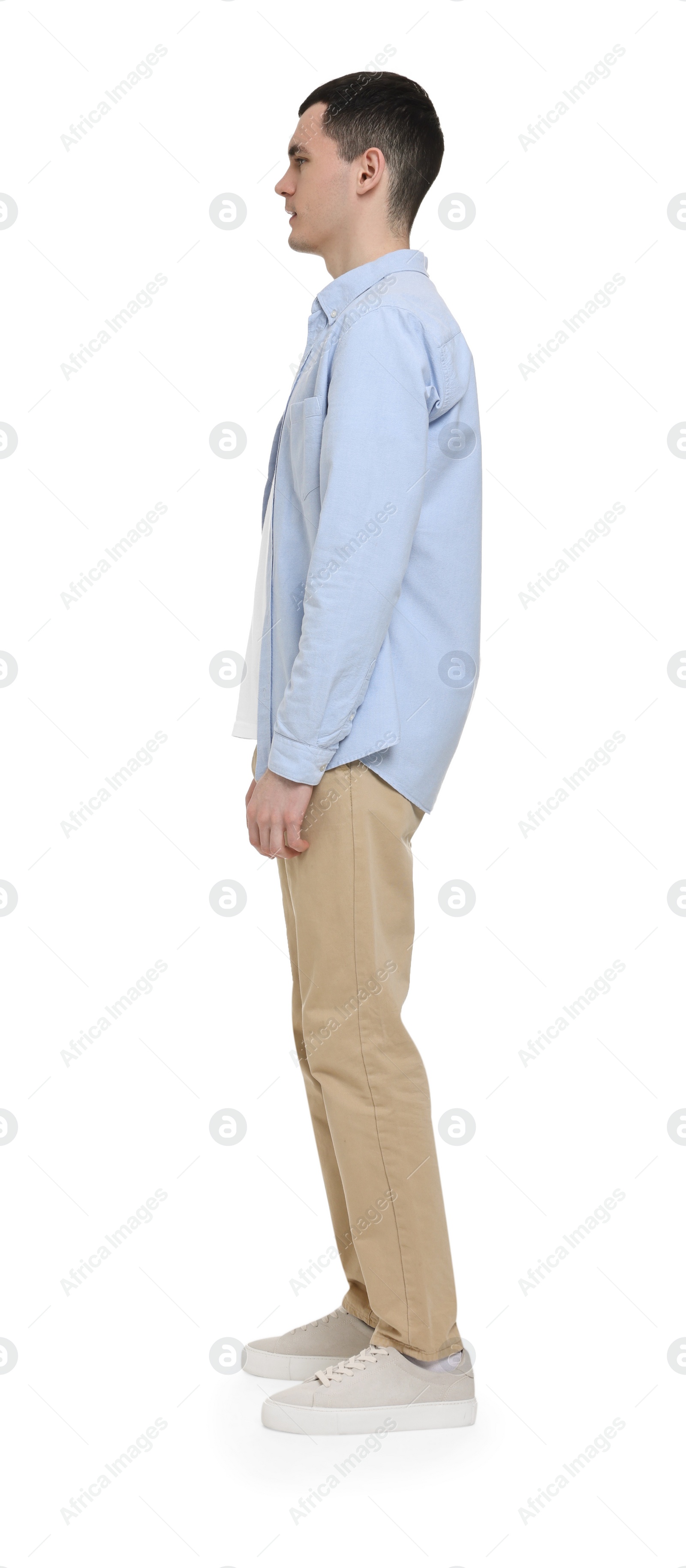 Photo of Young man in light blue shirt and beige pants on white background