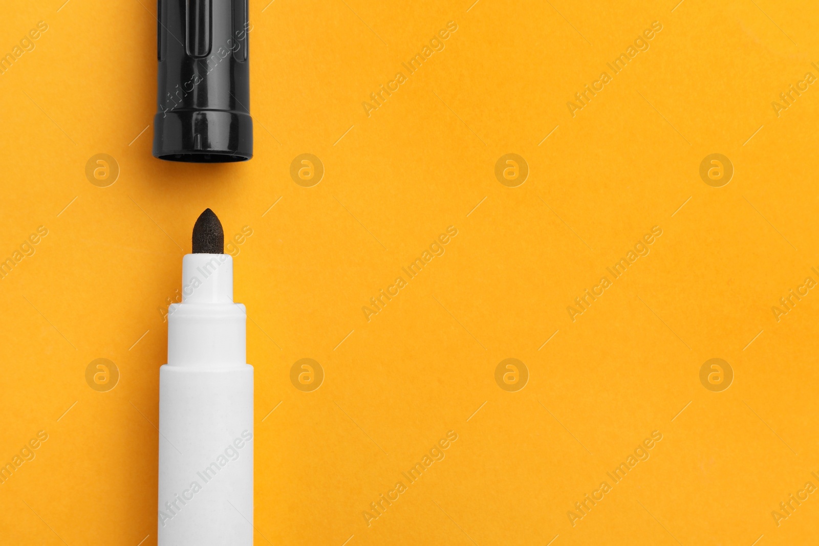 Photo of Black marker on orange background, flat lay. Space for text