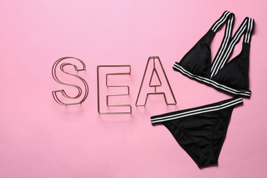Photo of Flat lay composition with bikini and word SEA on color background